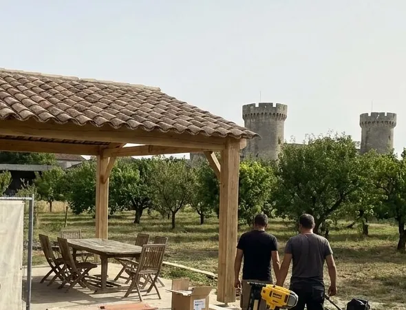 Auvent en tuiles canal sur poteaux de bois face aux tours du château de Châteaurenard